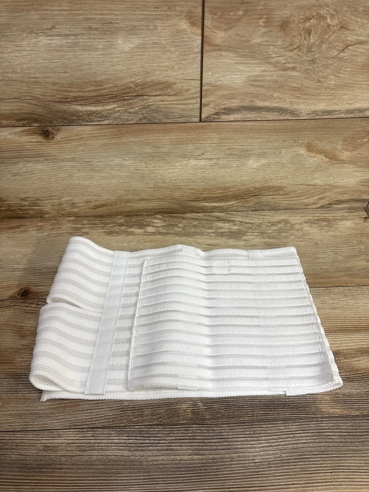 White postpartum belly band for maternity support on a wooden floor