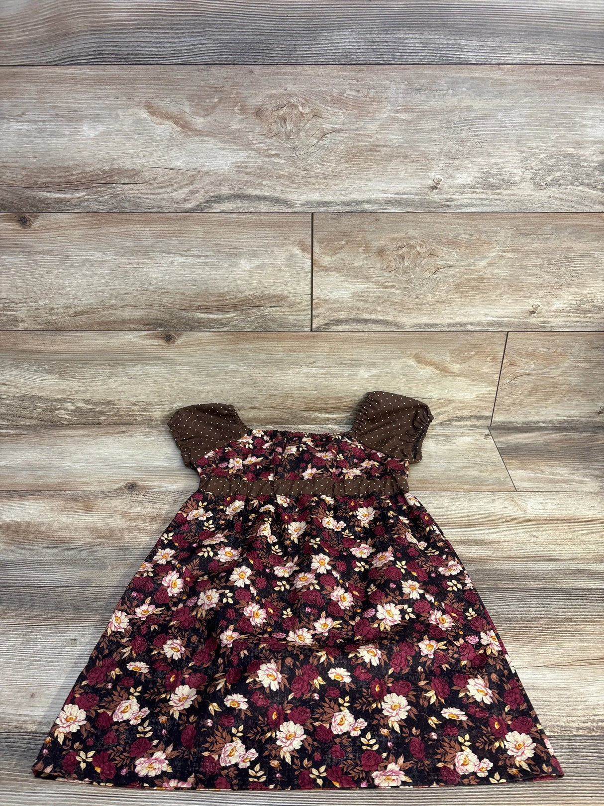Flat lay of girls' Vintage Cuties patchwork dress size 4T showing floral print with brown polka-dot puff sleeves on wood floor