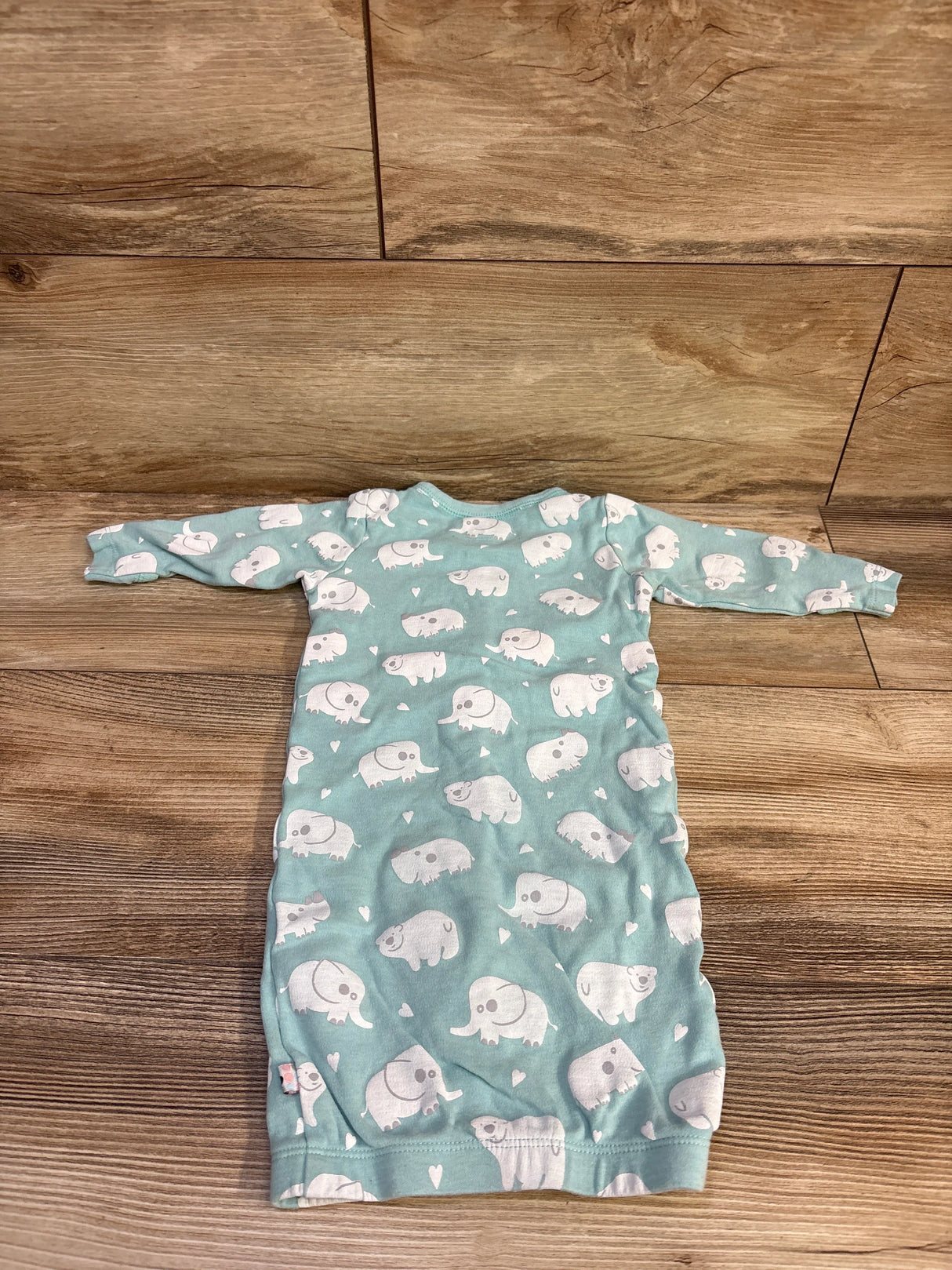 Flat lay of Babysoy snap sleep gown (3-6 months) showing white elephant print, long sleeves and cinched hem on wood floor