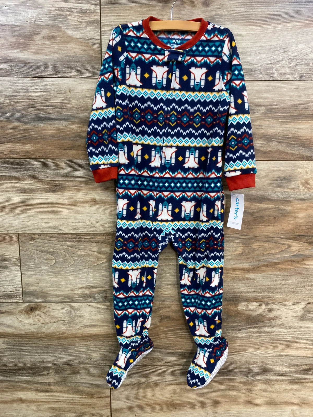 Front view of Carter’s navy footed sleeper showing rocket and southwestern pattern, red cuffs, built-in feet on wooden floor