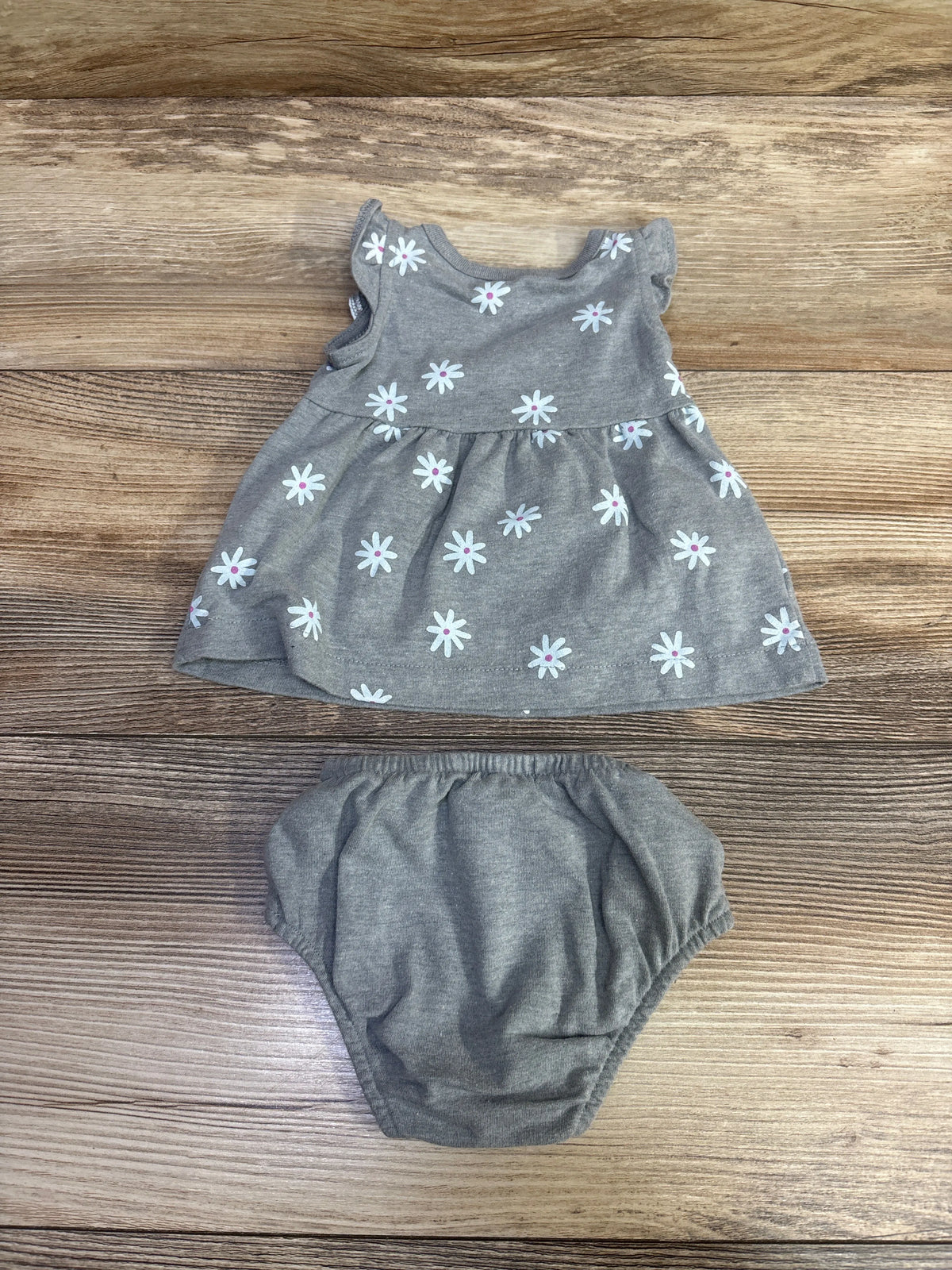 Top-down view of Cat & Jack 2pc newborn gray dress and bloomers set with floral print on a wood surface