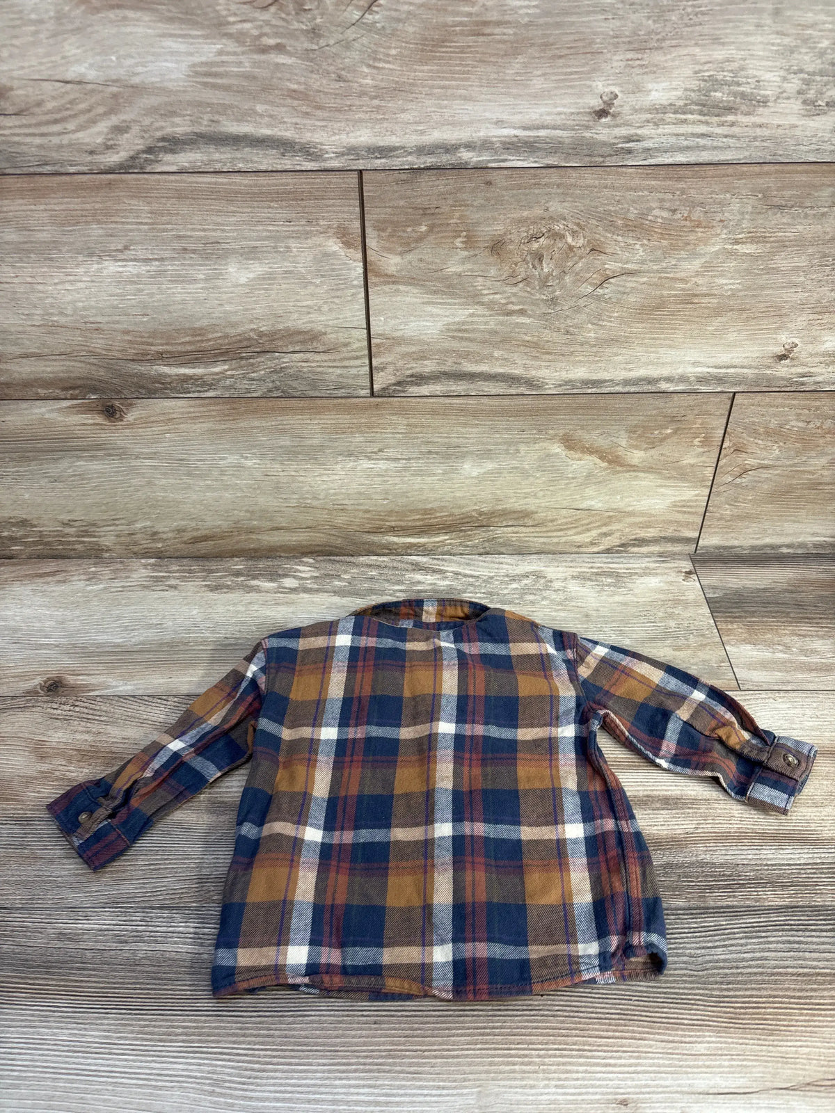 Front view of H&M Button-Up Flannel Navy sz 9m showcasing long sleeves, collar, and button cuffs on a wood background