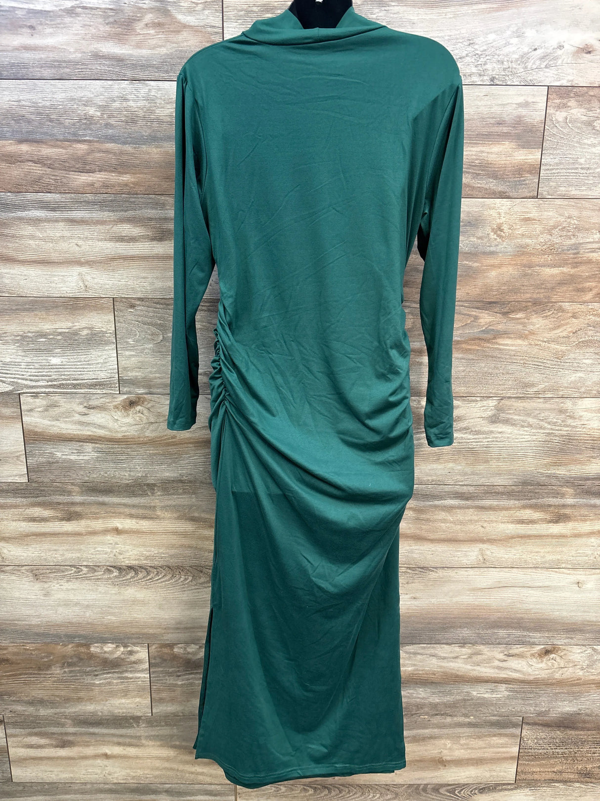 Green long-sleeve maternity dress with side ruching displayed on a black mannequin against wooden background