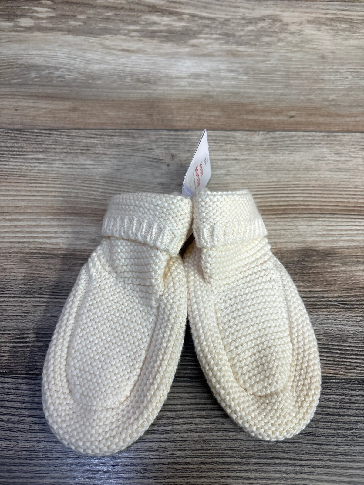 Top view of cream knit booties showcasing ribbed cuffs and textured knit construction on a wood grain surface