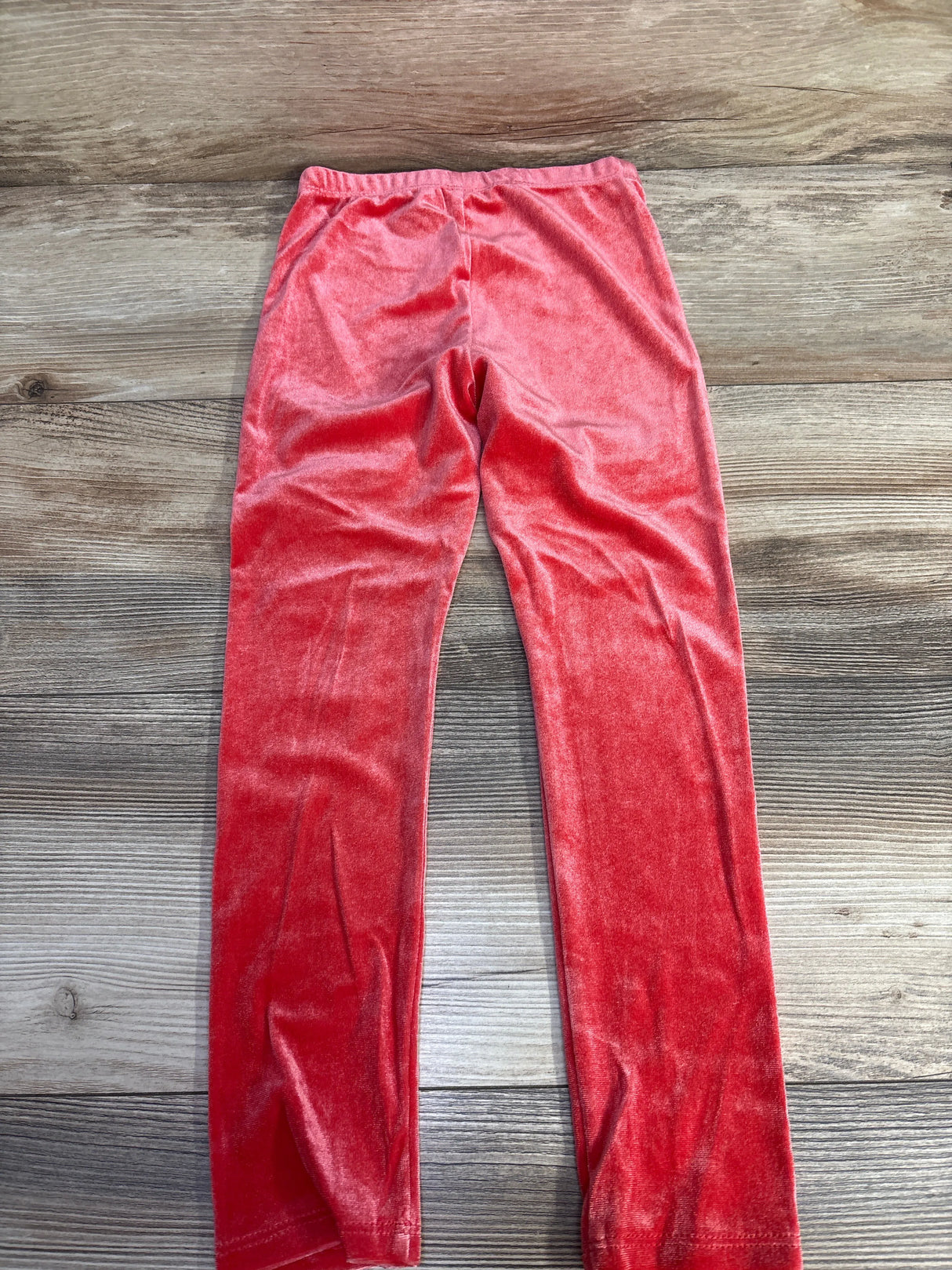 Red velvet children's leggings on wood background