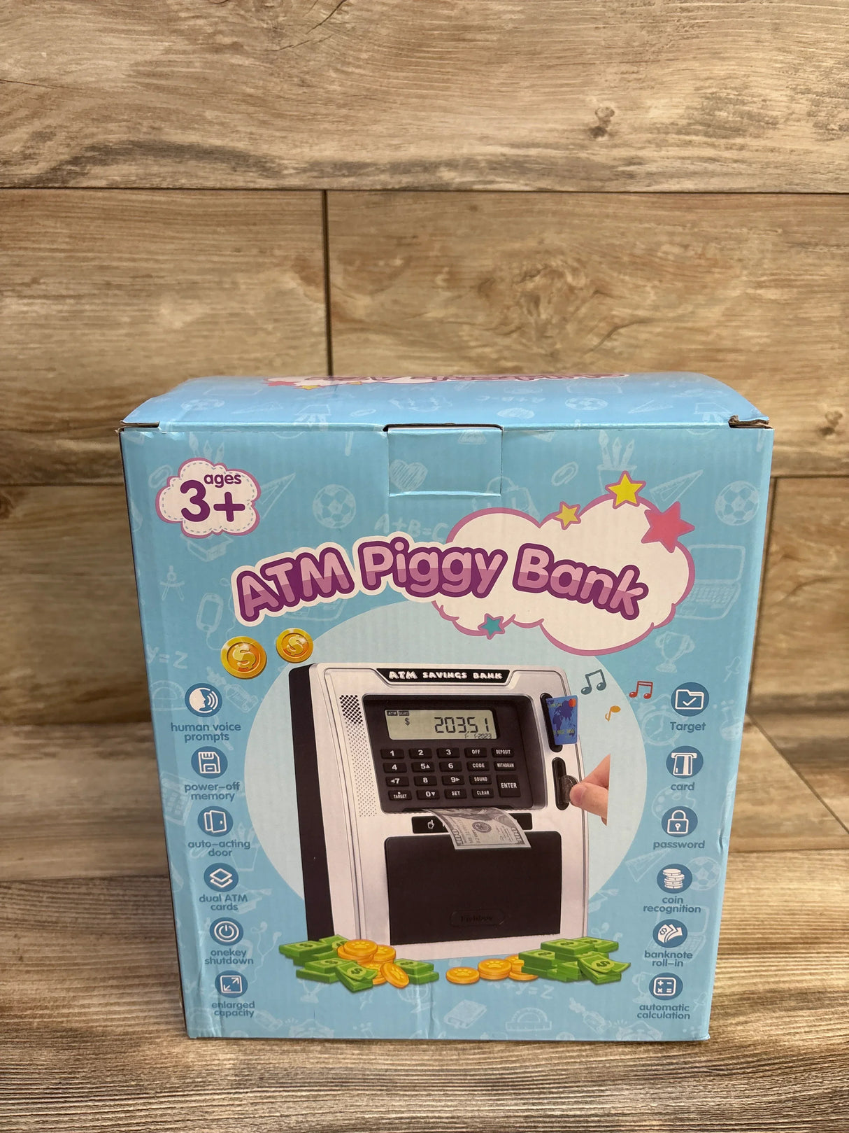 Front view of Fishboy talking ATM piggy bank showing keypad, LCD display, bill slot and coin tray on wooden floor background
