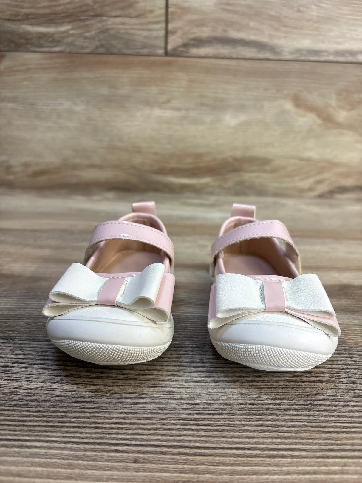 Pink and white baby girl shoes with bows on wooden floor, kids footwear