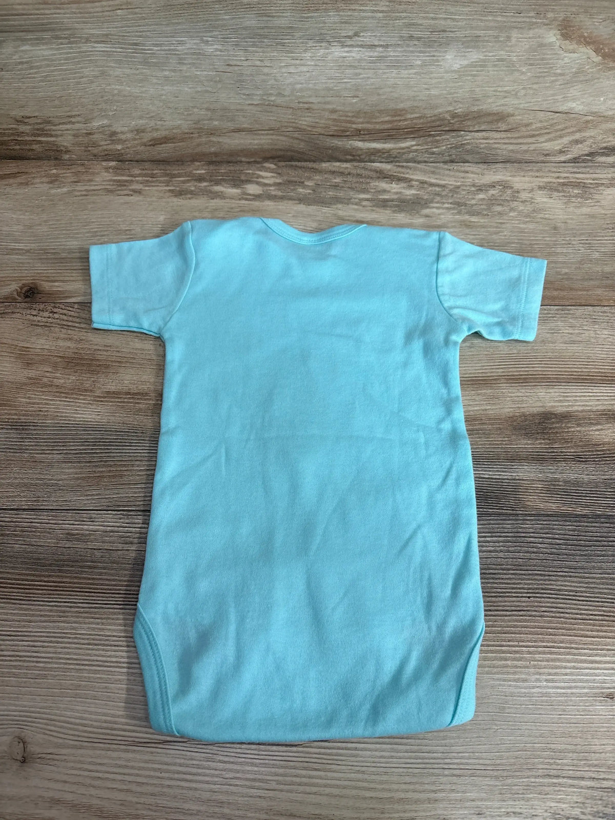 Back view of Laughing Giraffe Super Fly Bodysuit showcasing solid light blue fabric and short sleeves on wood background