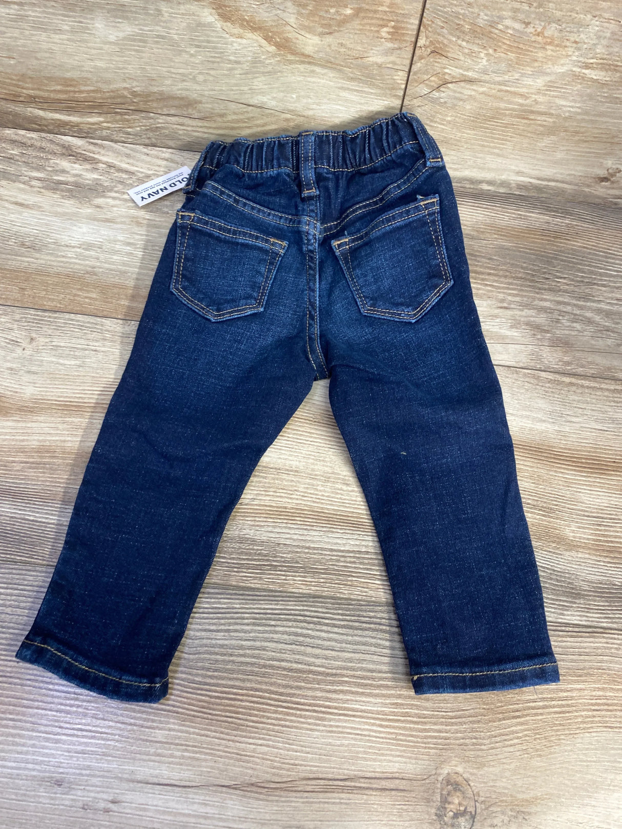 Dark wash toddler jeans with elastic waistband and back pockets on wood surface