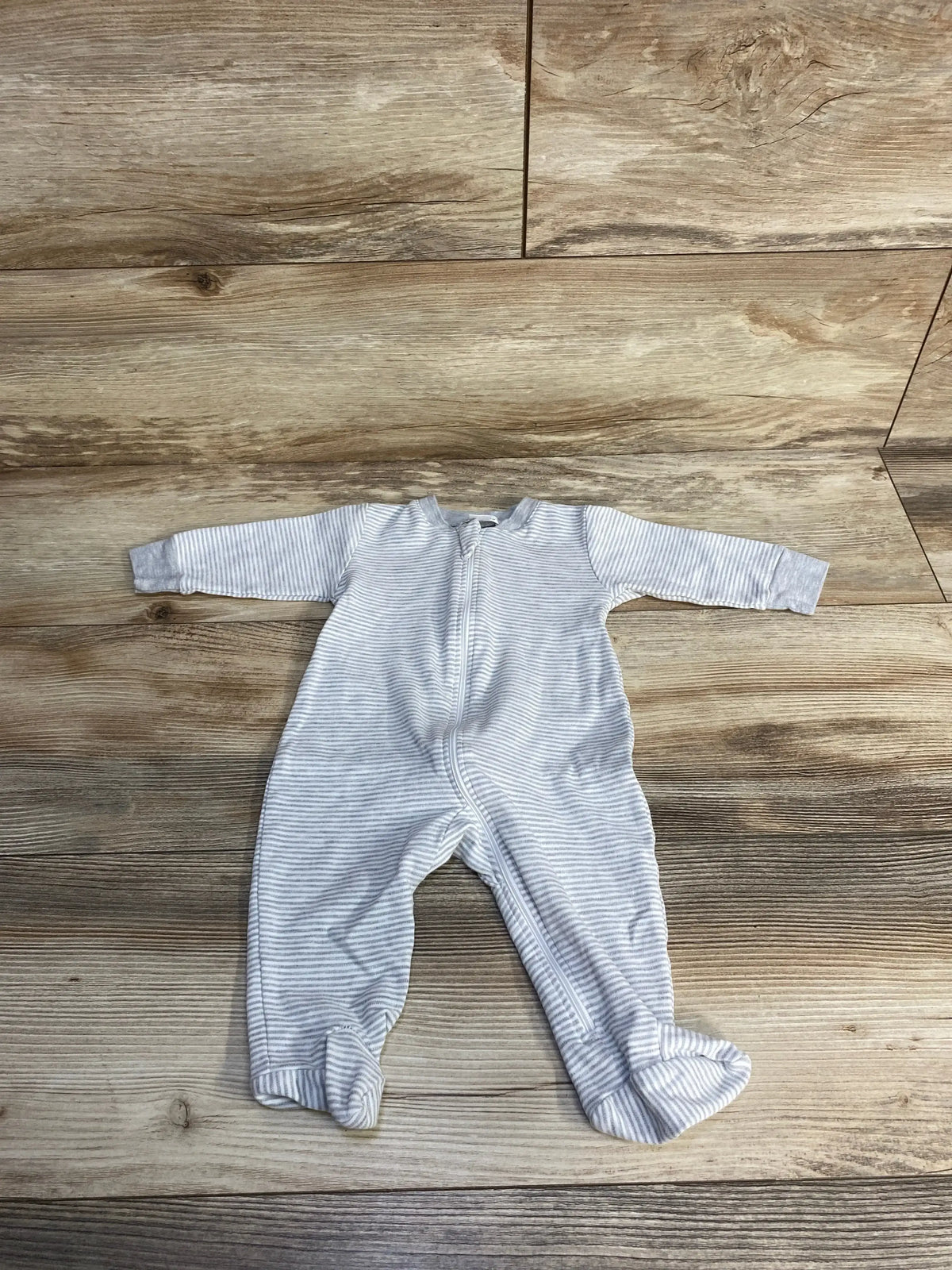 Gray striped baby onesie with zipper on a wooden floor