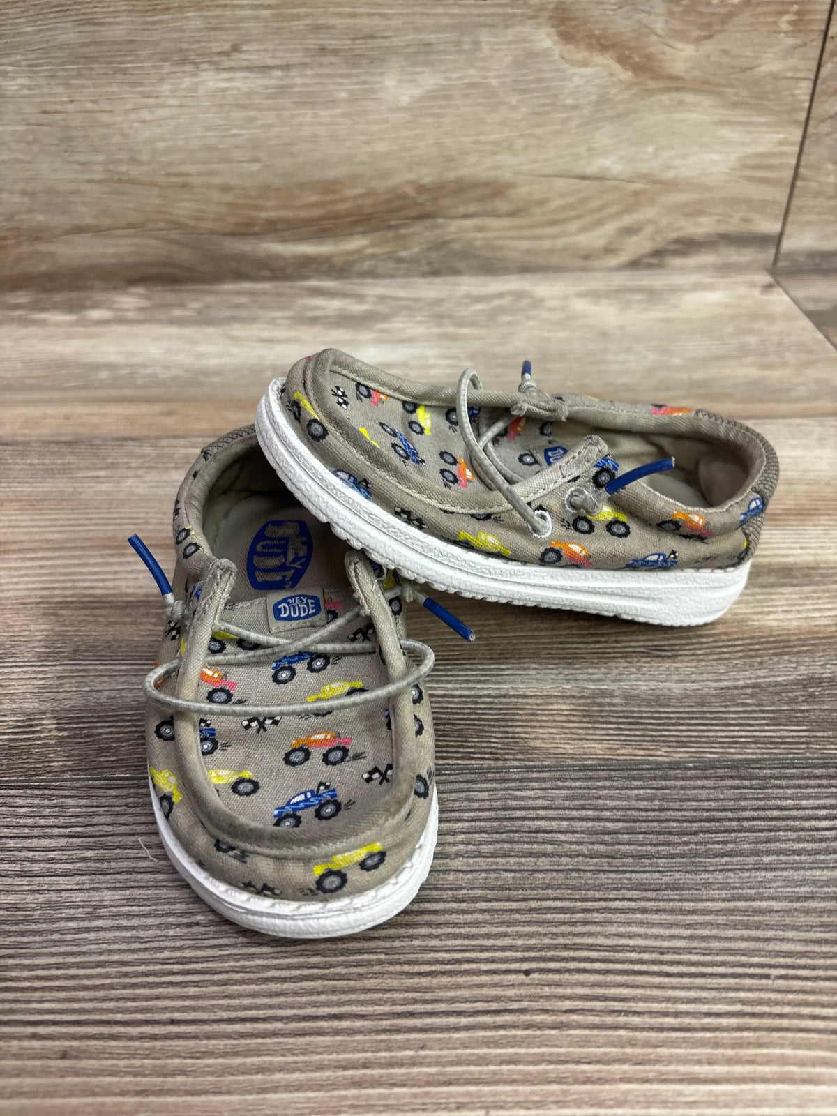Tan Hey Dude Wally T toddler shoes with colorful truck pattern and blue laces.