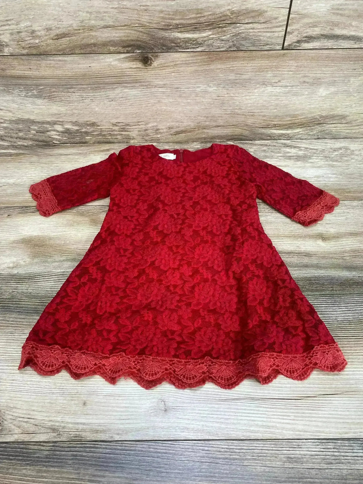 Flat lay of red toddler lace dress size 3T showcasing floral lace overlay, 3/4 sleeves and scalloped hem on wood background