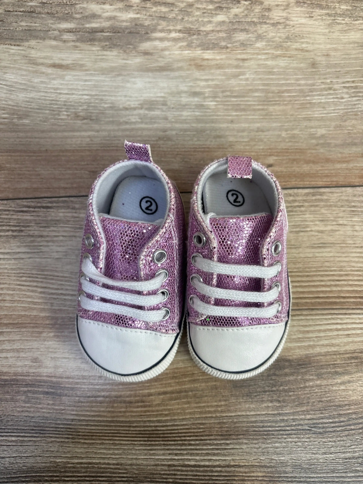 Pair of Me n Mommy To Be glittery purple slip-on crib shoes size 2c on a wooden surface