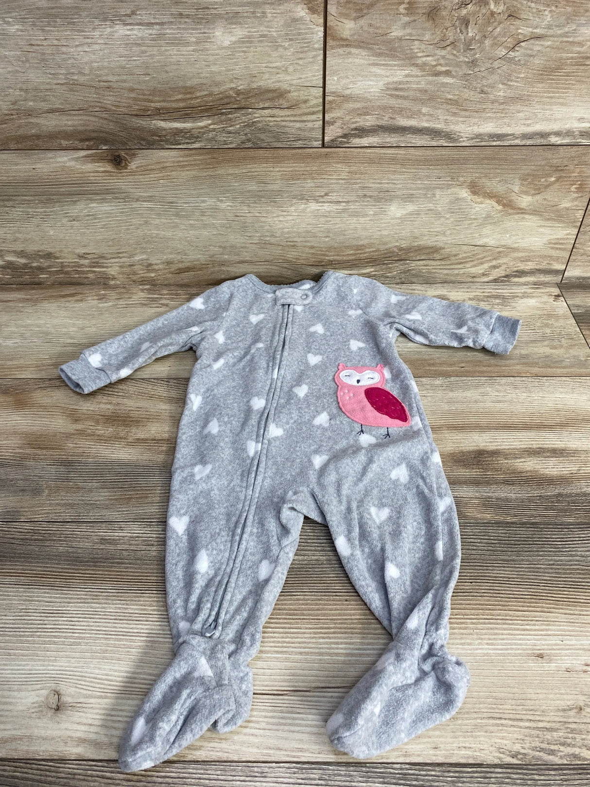 Gray baby onesie with white hearts and pink owl patch on wooden floor