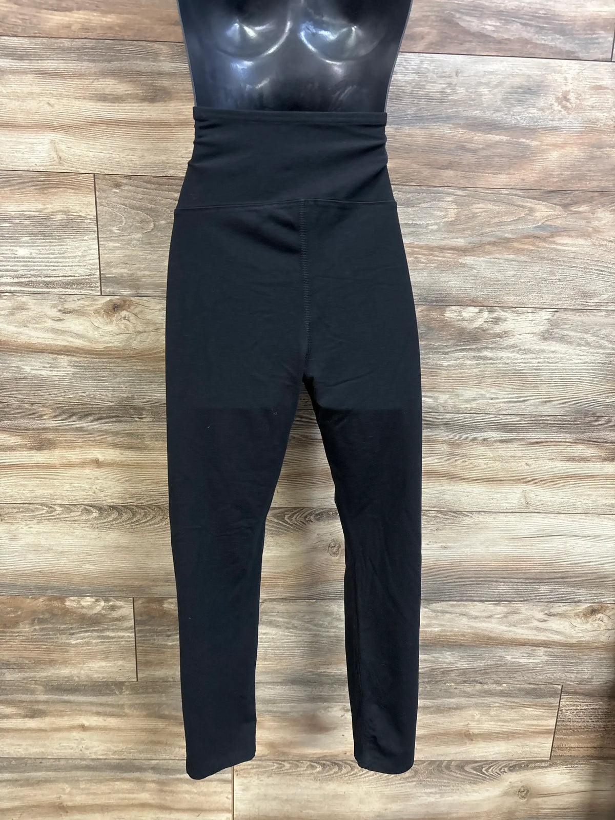 Front view of black maternity leggings showcasing an over belly waistband and full length fit on a mannequin against a wood floor