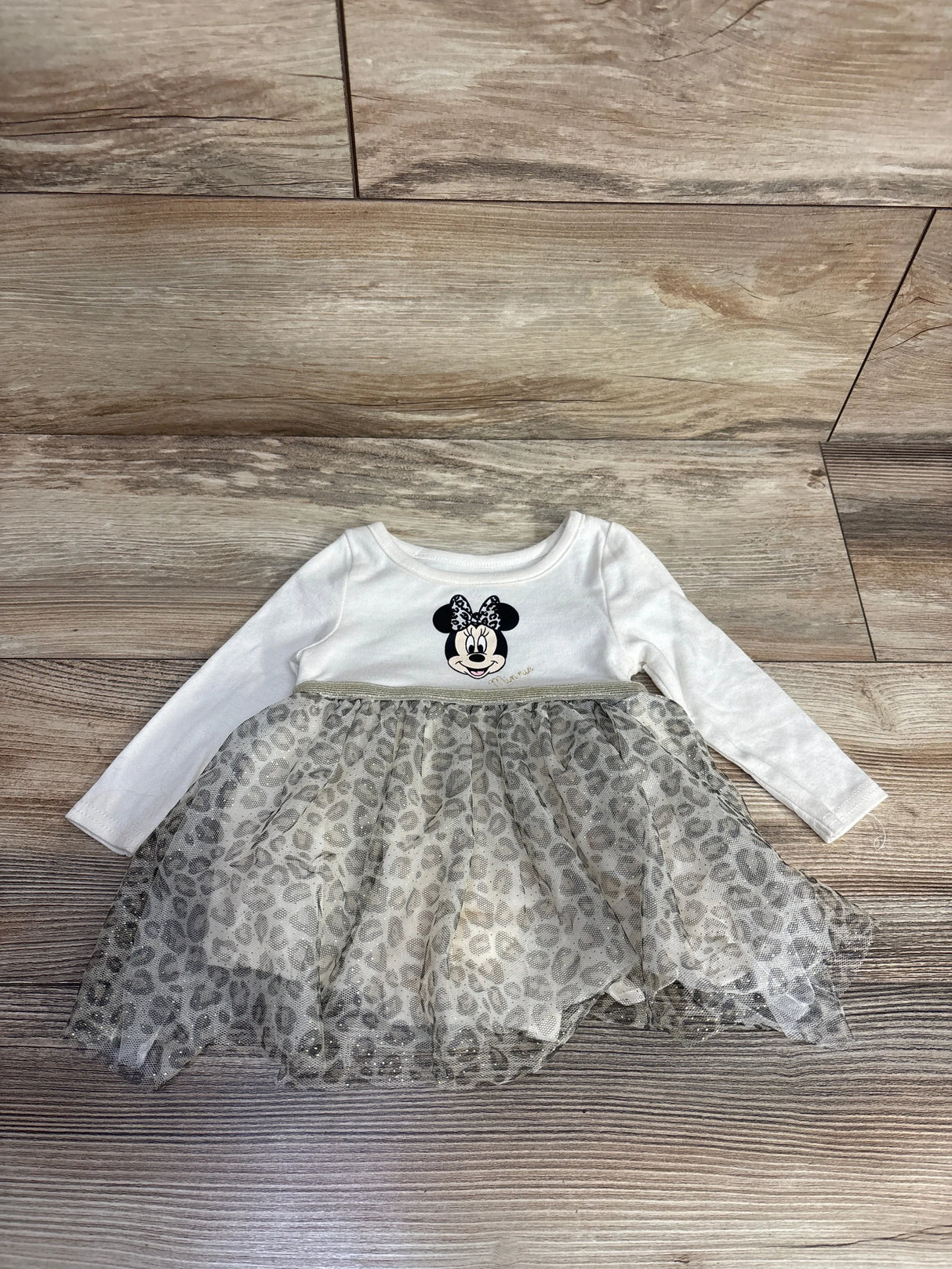 Baby girl dress with Minnie Mouse print and leopard tulle skirt on wood floor