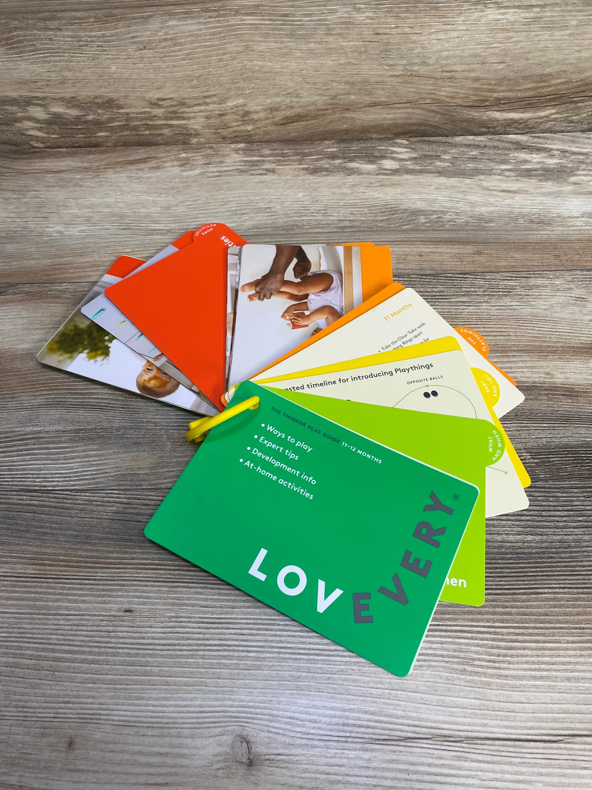 Lovevery play guide cards with expert tips, development info, and at-home activities on wood surface