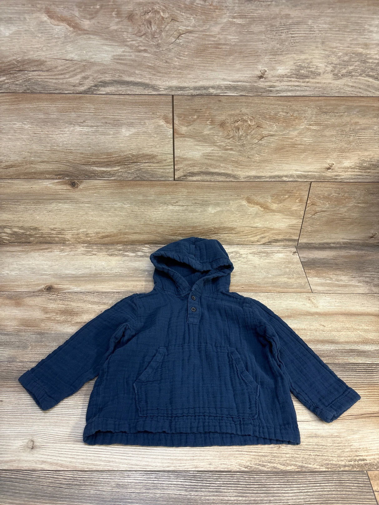 Navy blue toddler hoodie with front buttons and pocket on wood background