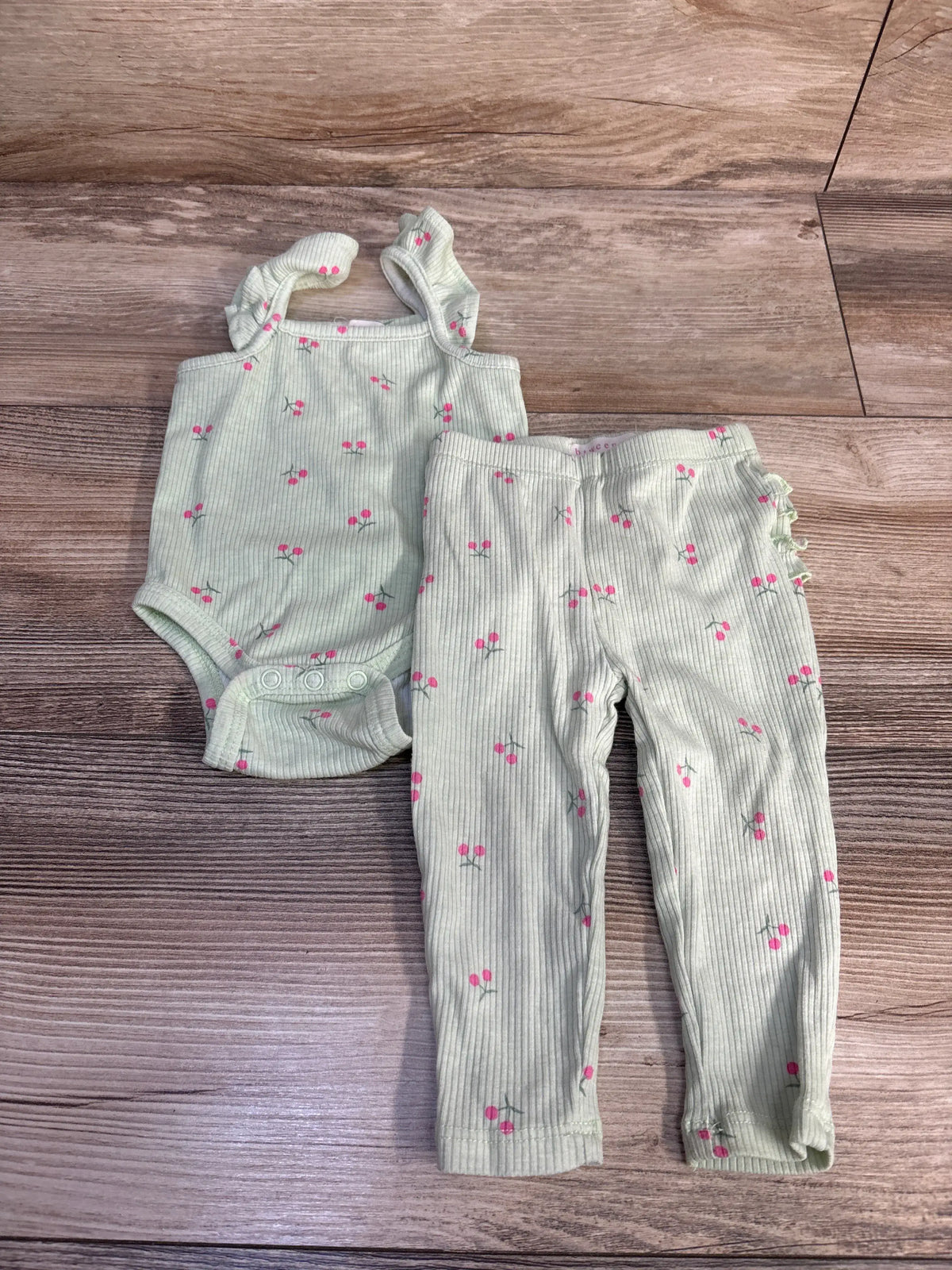 Front view of Btween baby 2-piece ribbed tank bodysuit and pants set in green with pink floral print on a wood-grain background