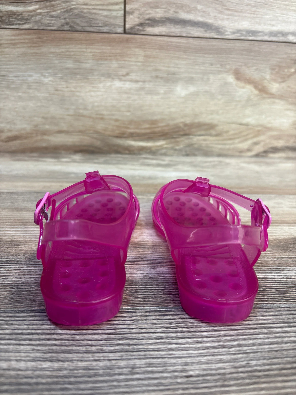 Front view of Janie and Jack Jelly Fisherman sandals in pink, size 9C, showing adjustable buckle straps and dotted footbed on wood floor