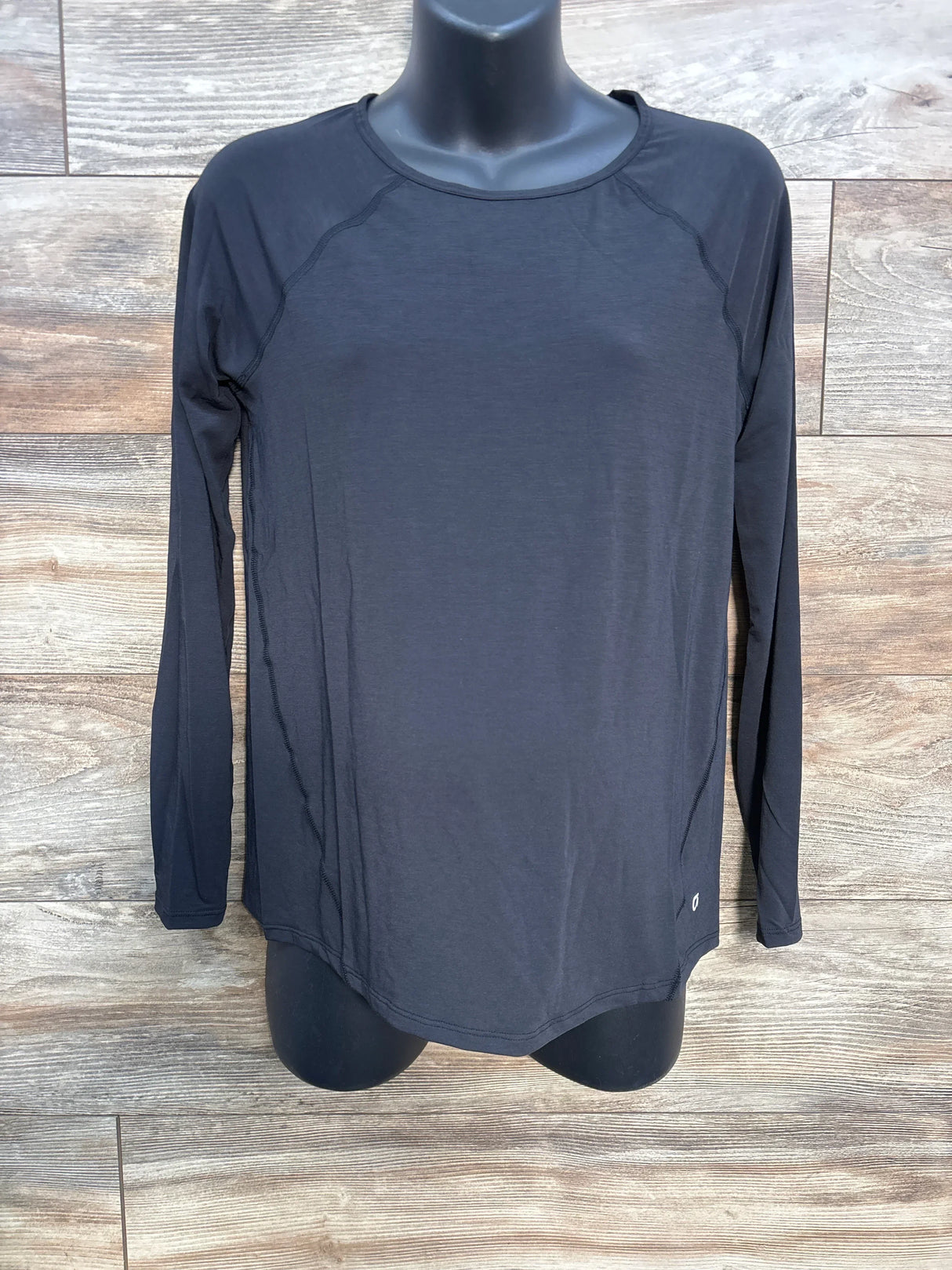 Black long sleeve athletic shirt on mannequin against wood background