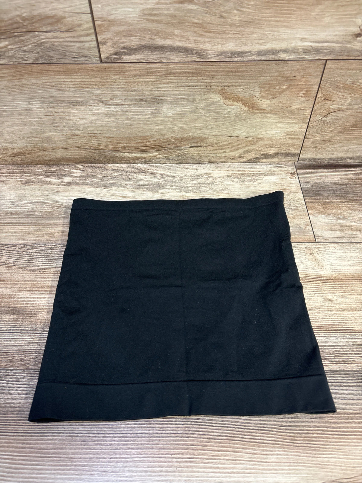 Top view of Isabel Maternity BellaBand in black, size medium large, laid flat on a wood-look floor