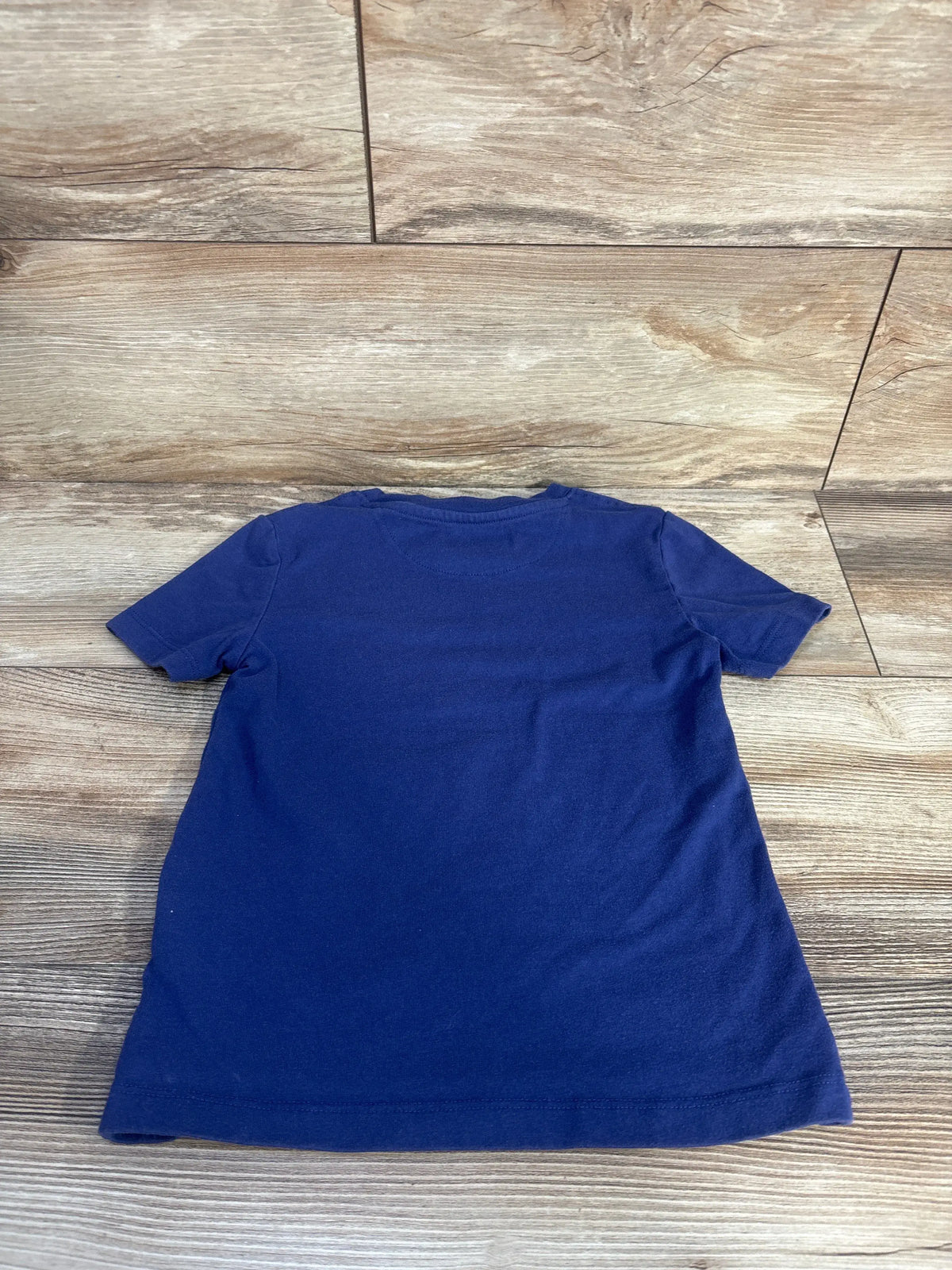 Back view of navy blue toddler T-shirt Adventure360 size 5T showing short sleeves and plain back on wood floor