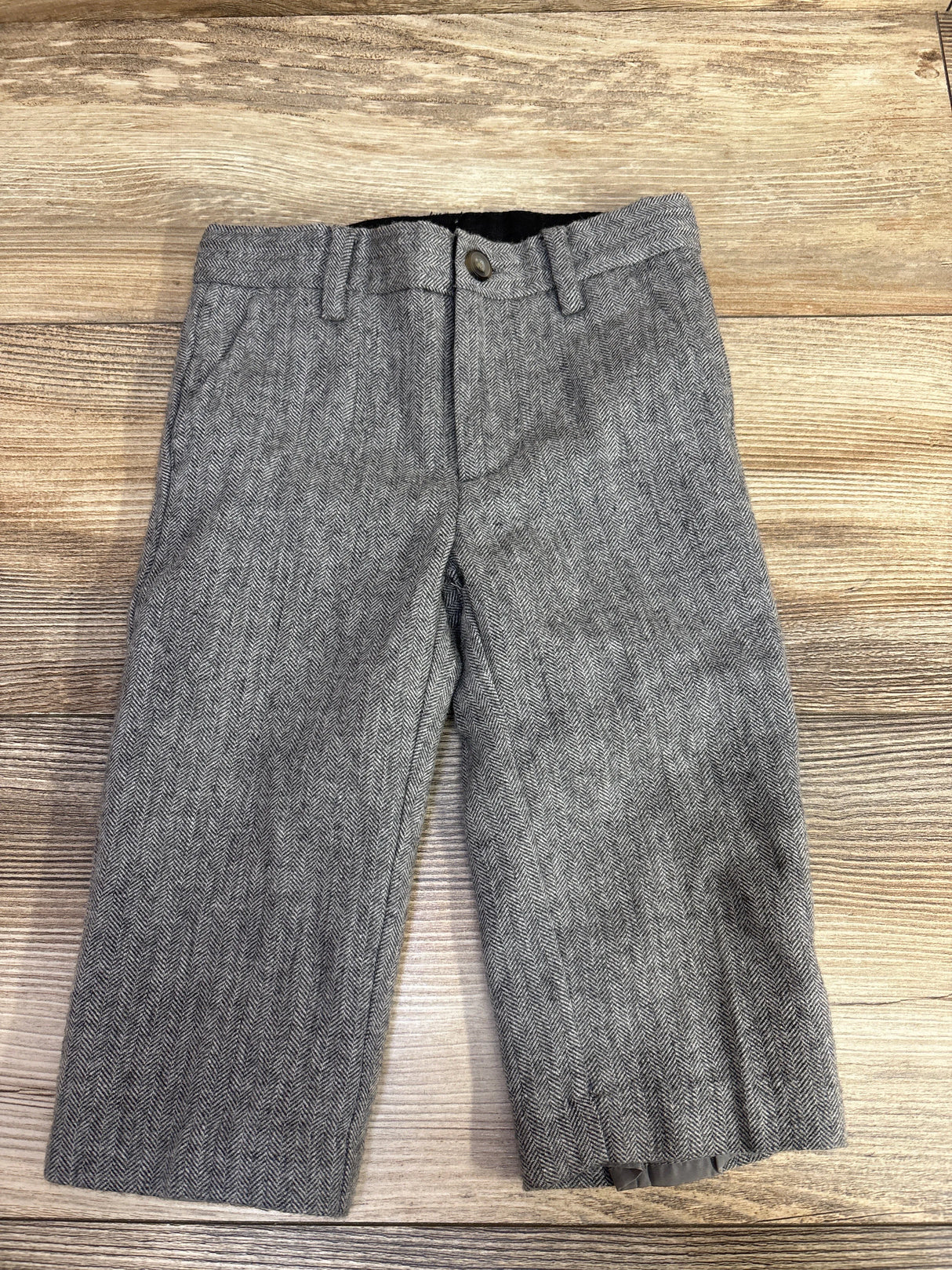 Gray herringbone pattern toddler pants with button and belt loops on wooden background