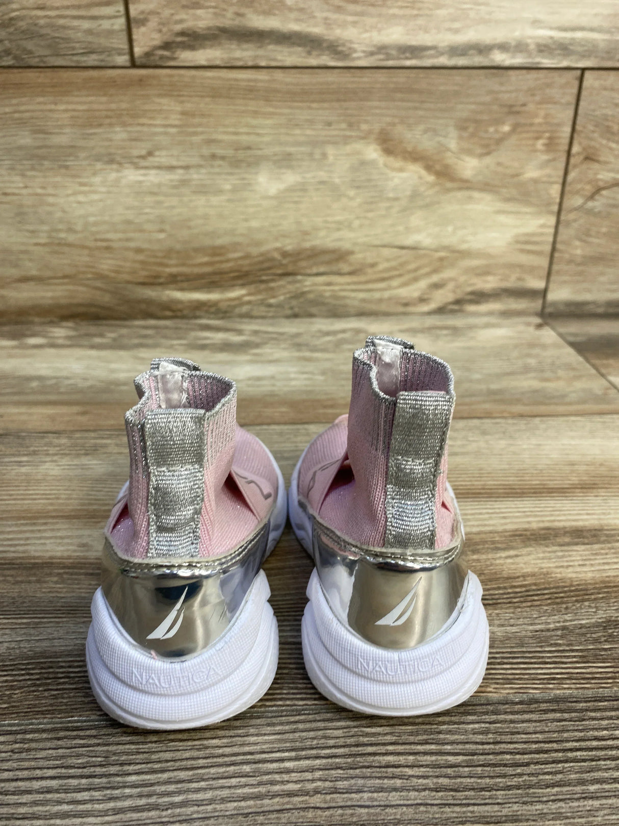 Rear view of Nautica pink slip-on sock-style toddler sneakers size 6C showing metallic heel panels and white textured soles on wood floor