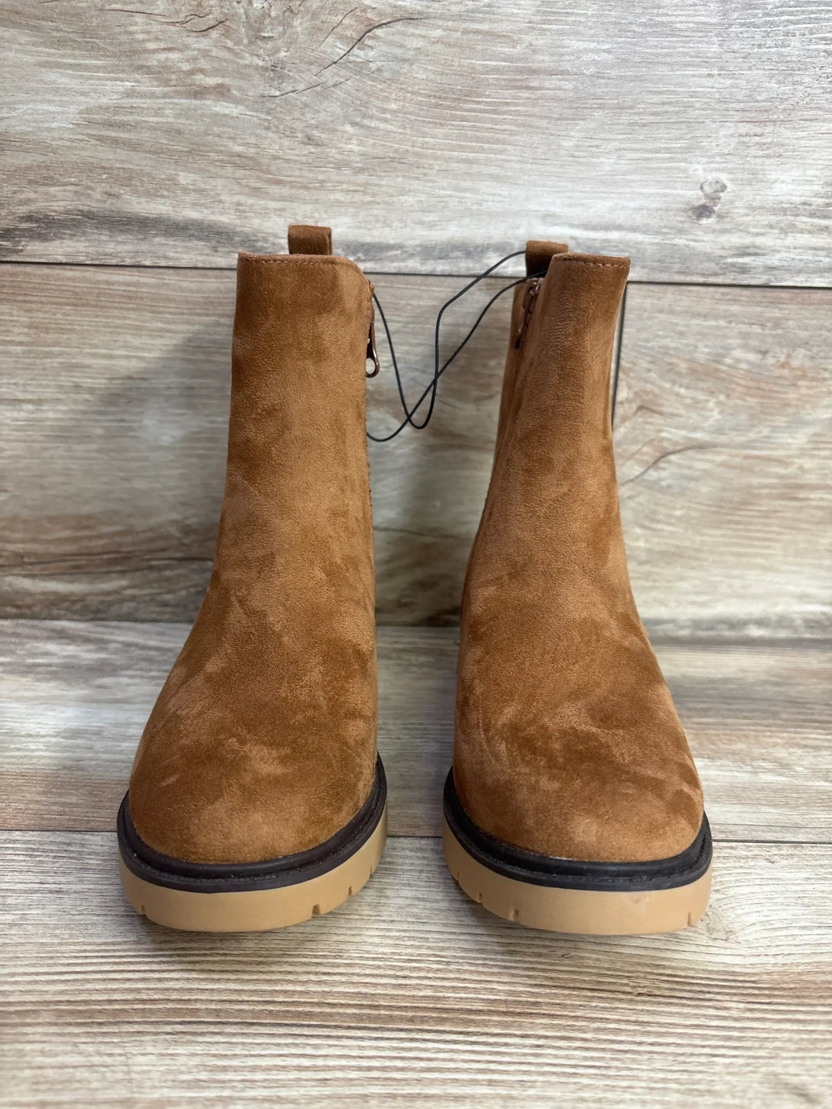 Pair of brown suede children's boots with side zippers on a wood background