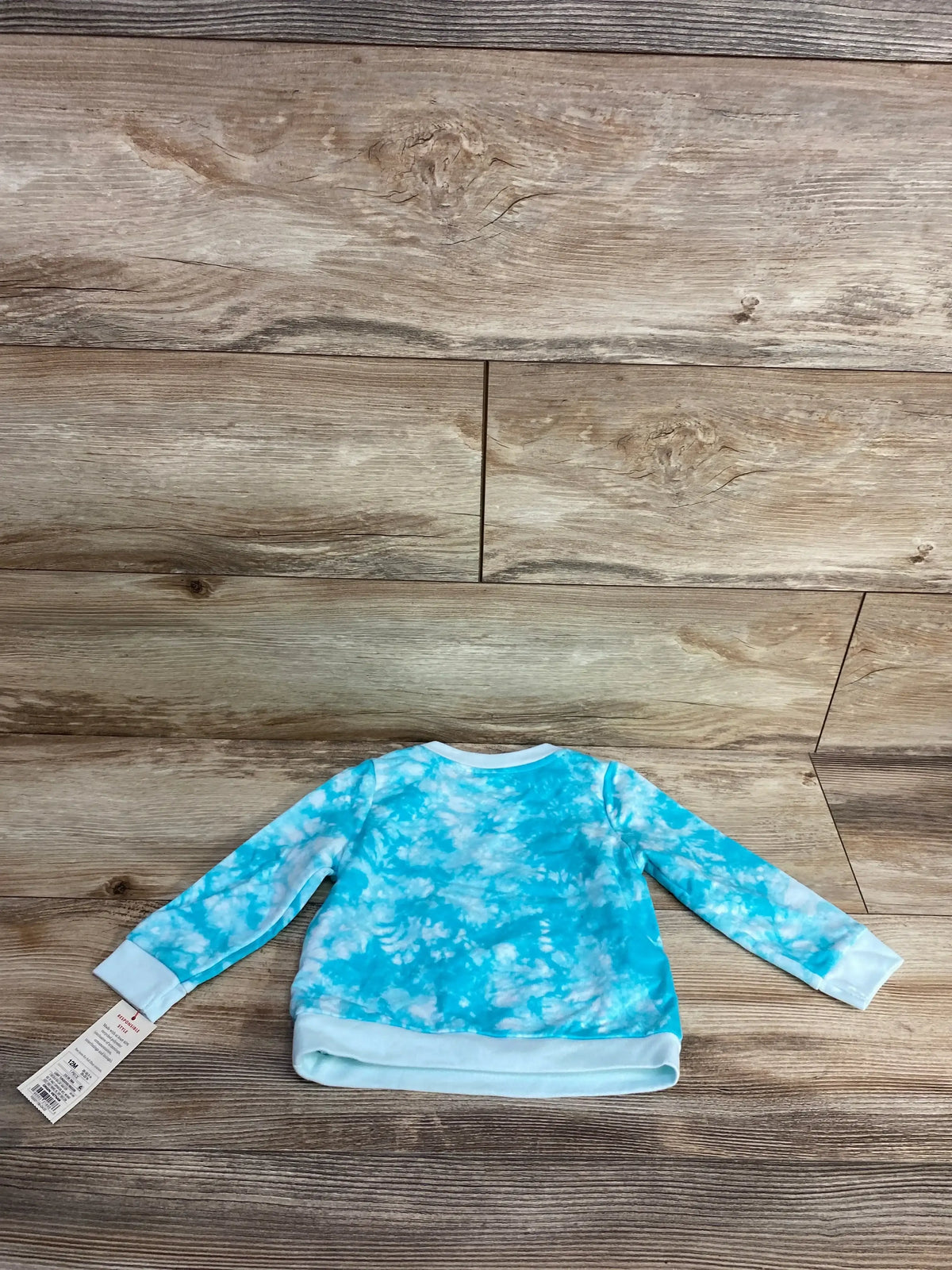 Blue and white tie-dye long sleeve toddler shirt on wood background with tag attached