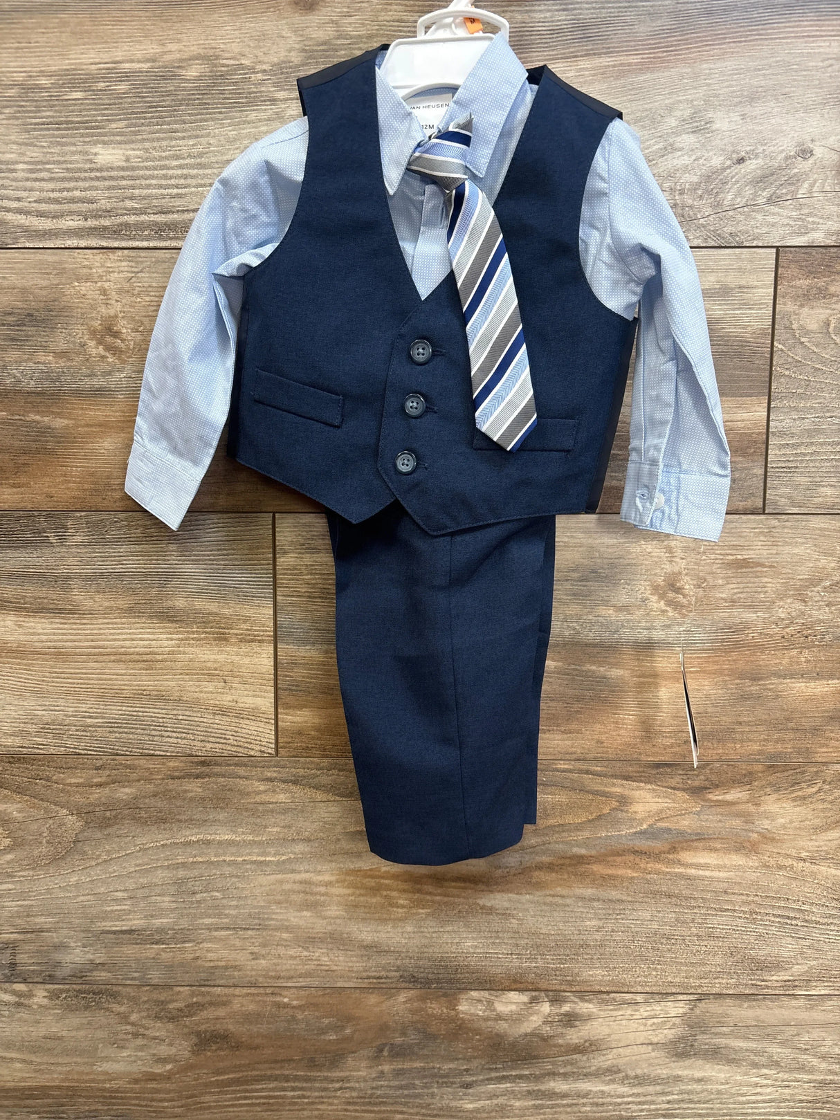 Front view of Van Heusen 4-piece 12M suit: navy three-button vest, striped tie, light blue shirt, and navy pants on wood floor