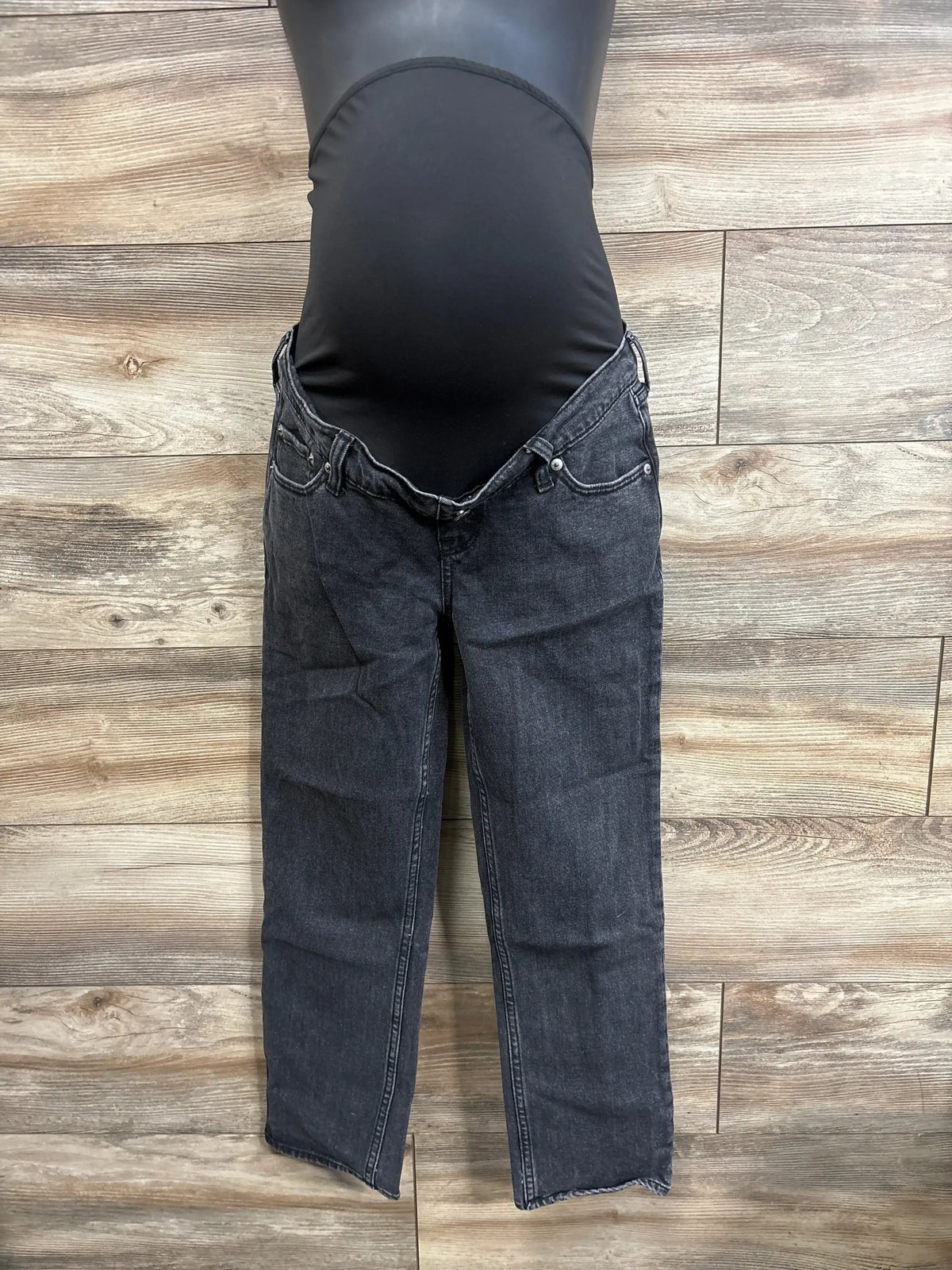 Front view of Abercrombie & Fitch ‘90s maternity straight black jeans showing low-rise waist and straight legs on mannequin against wood plank background