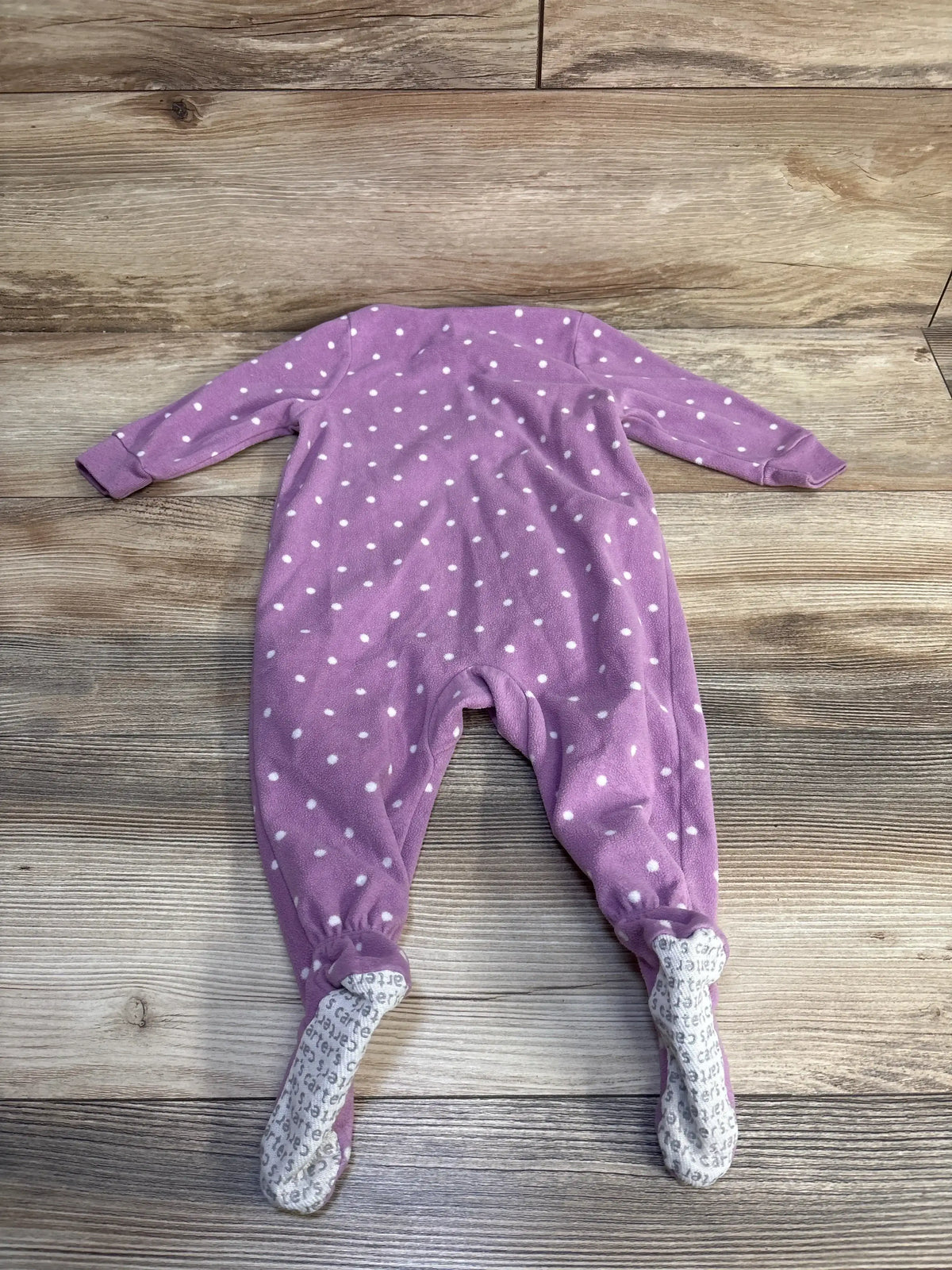 Back view of purple Carter’s fleece footed blanket sleeper with white polka dots and gray nonslip soles on wood floor