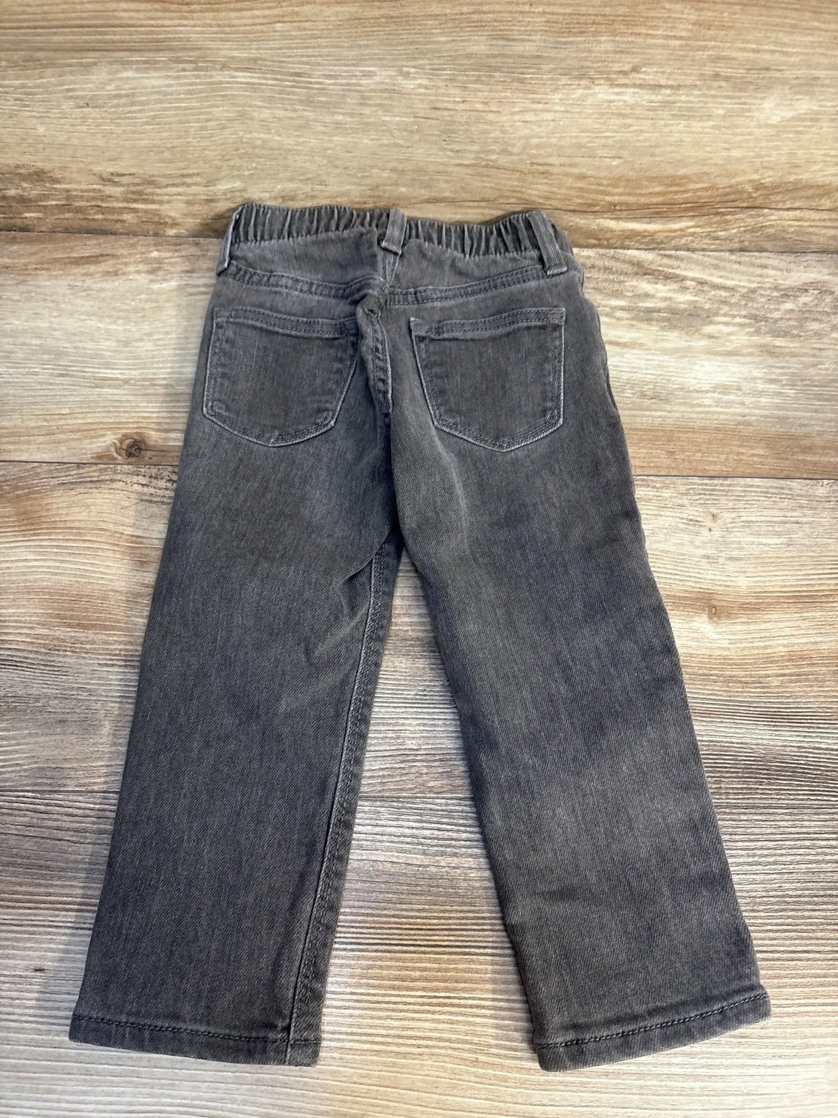 Gray children’s jeans with elastic waistband and back pockets on wood background