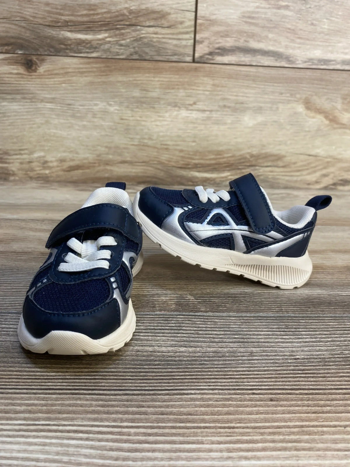 Three-quarter view of H&M lightweight-sole navy toddler sneakers size 5.5C showing velcro strap and white sole on wood background