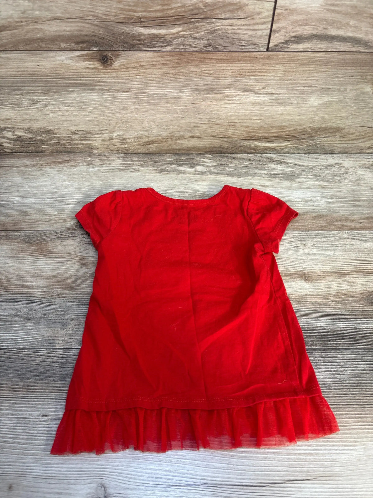 Back view of Disney Elena of Avalor red tulle peplum shirt with short sleeves and ruffle hem on wood floor