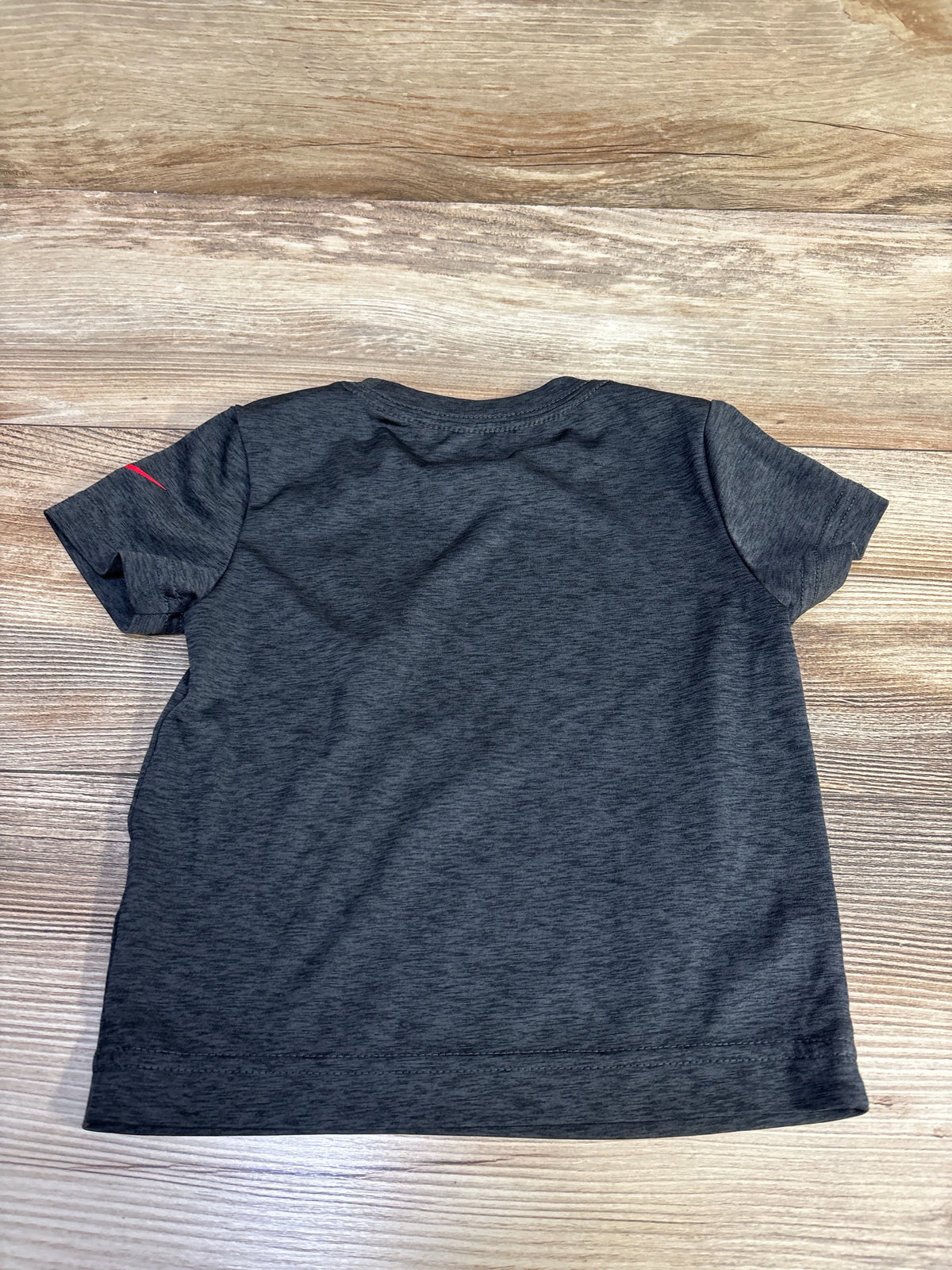 Back view of a grey Nike Dri-Fit short sleeve shirt for toddlers size 2T on a wooden background