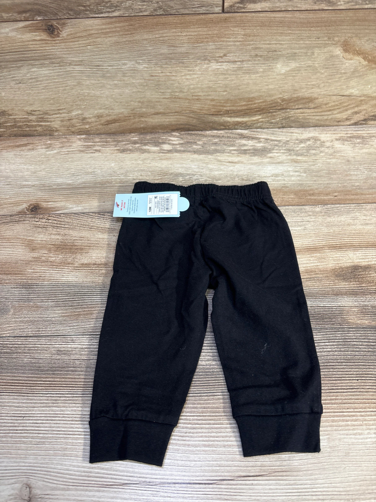 Flat lay of Cat & Jack black pull-on toddler joggers showing elastic waistband and ribbed ankle cuffs on light wood background