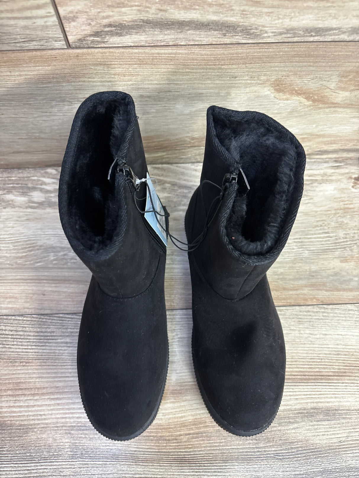 Pair of black suede toddler boots with soft fleece lining on wooden floor