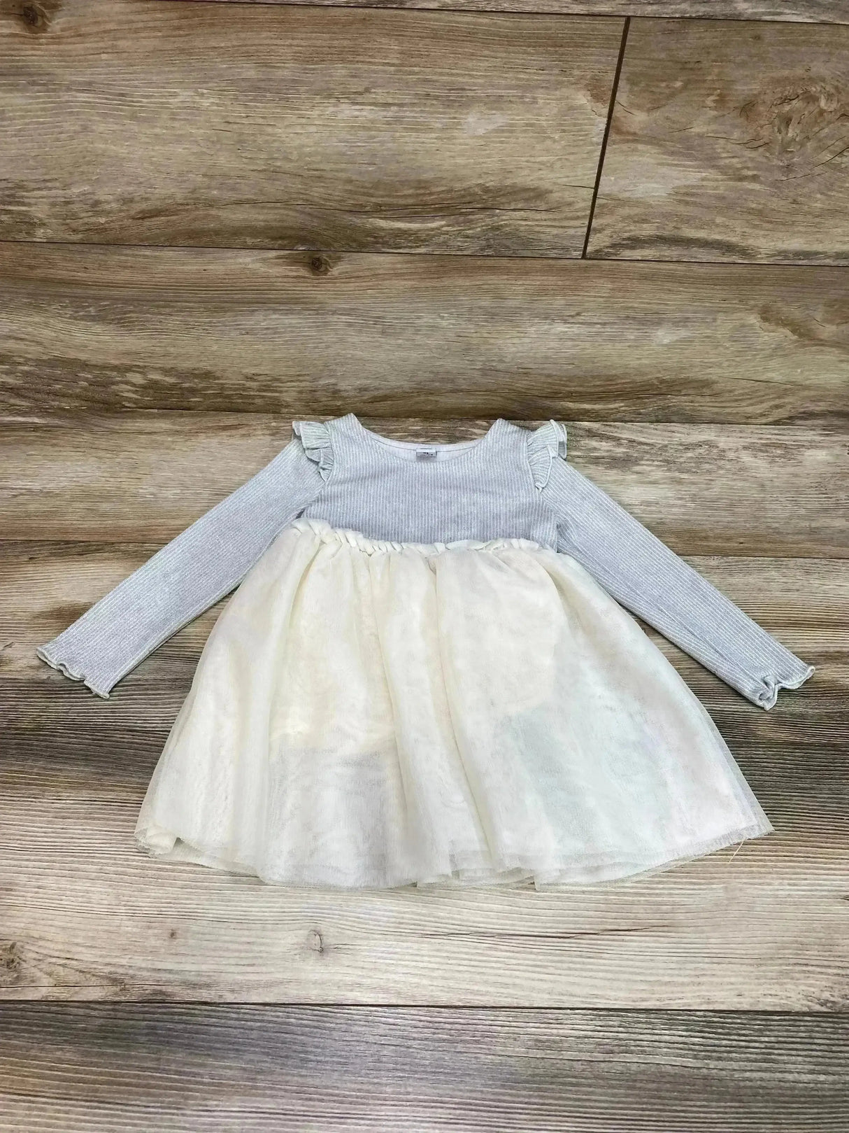 Flat lay of grey rib-knit Old Navy toddler fit-and-flare dress with ruffle shoulders and ivory tulle skirt on wood background