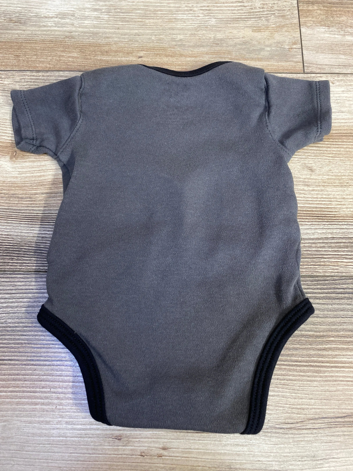 Gray short-sleeve baby bodysuit on wooden floor, plain back view, minimalist design