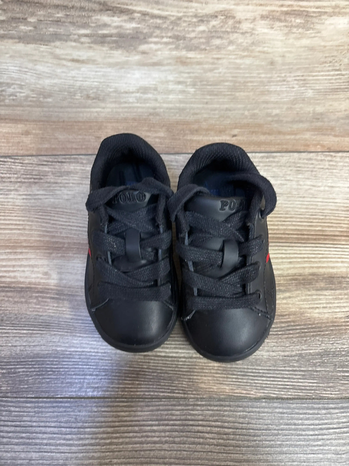 Top-front view of Polo Ralph Lauren Quilton Bear sneakers in black, showcasing lace-up styling on wood grain
