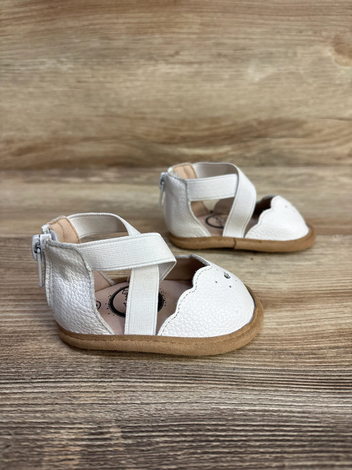 Angled front view of Little Love Bug Sophia white toddler shoes with scalloped toe, elastic cross straps and back zipper