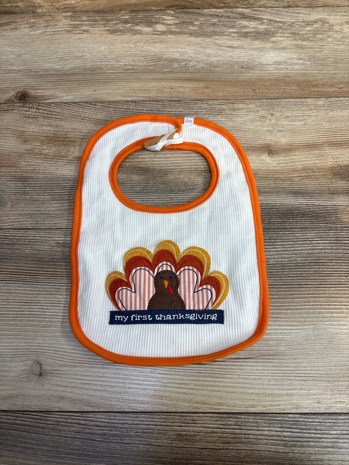 Baby bib with turkey and 'my first thanksgiving' text on wood background