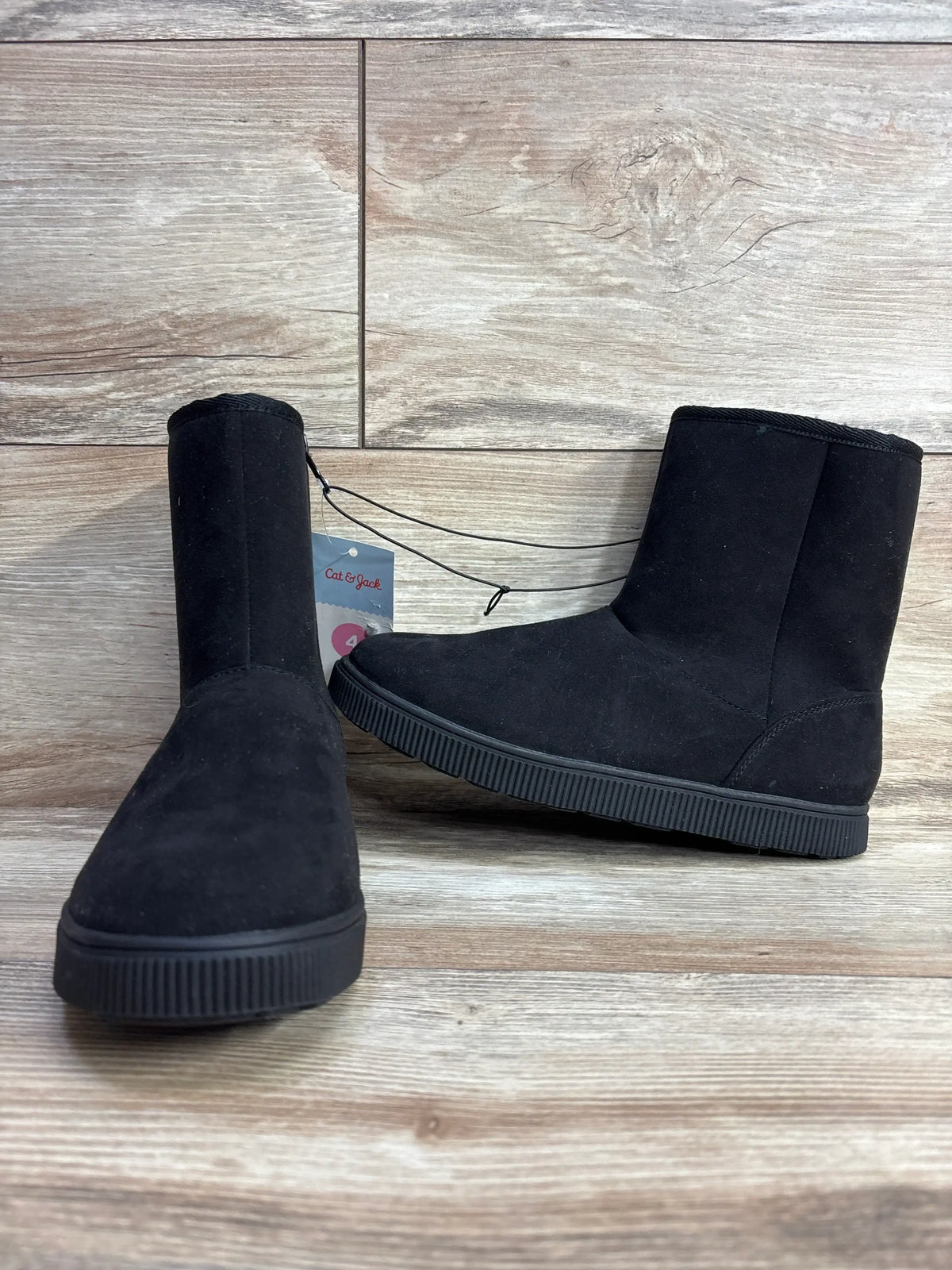 Three-quarter view of Cat & Jack kids’ black shearling-style boots size 4Y with faux-suede upper, plush lining and ribbed sole on wood floor