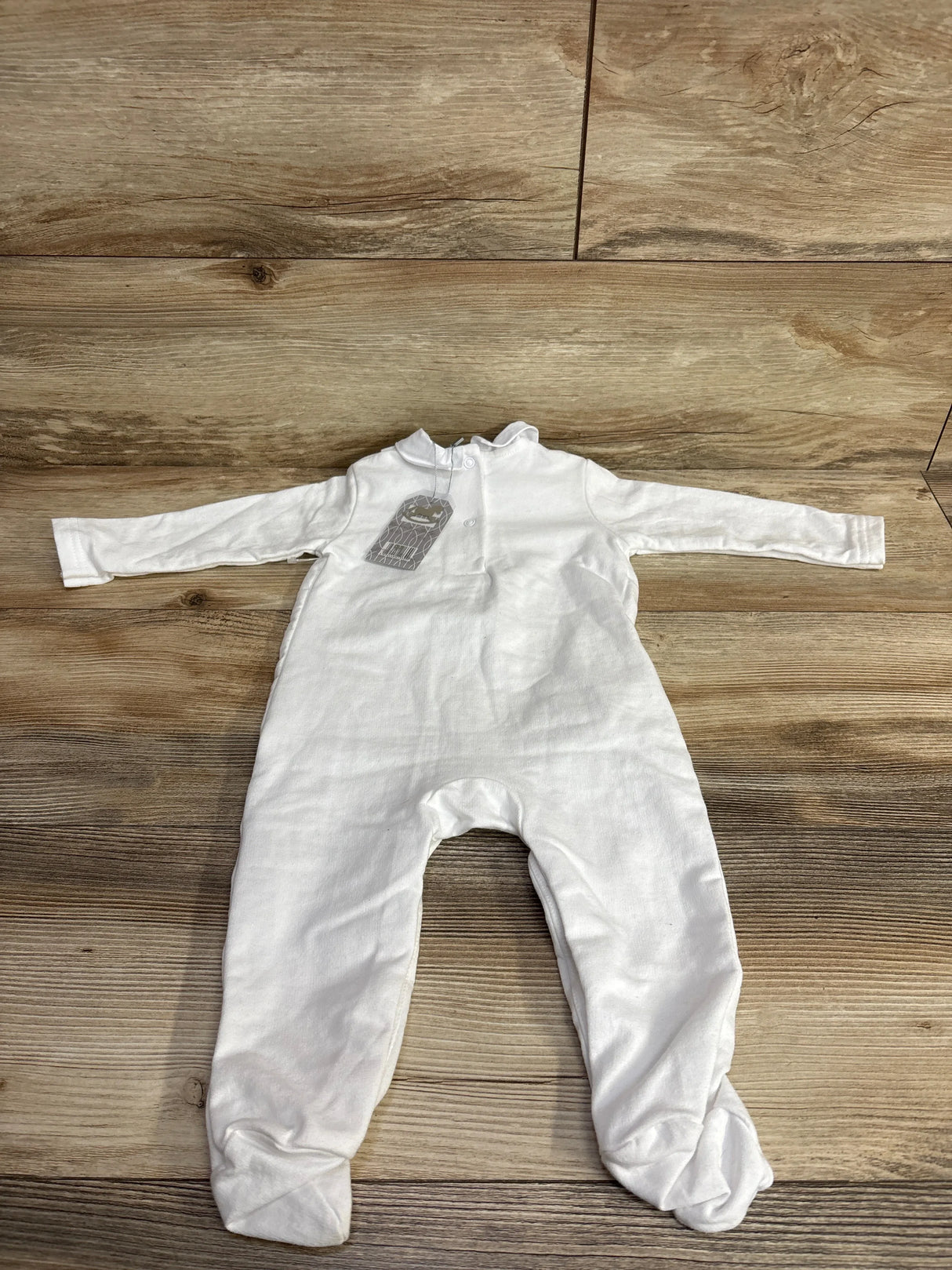 White long sleeve baby footed sleeper laid flat on wooden background