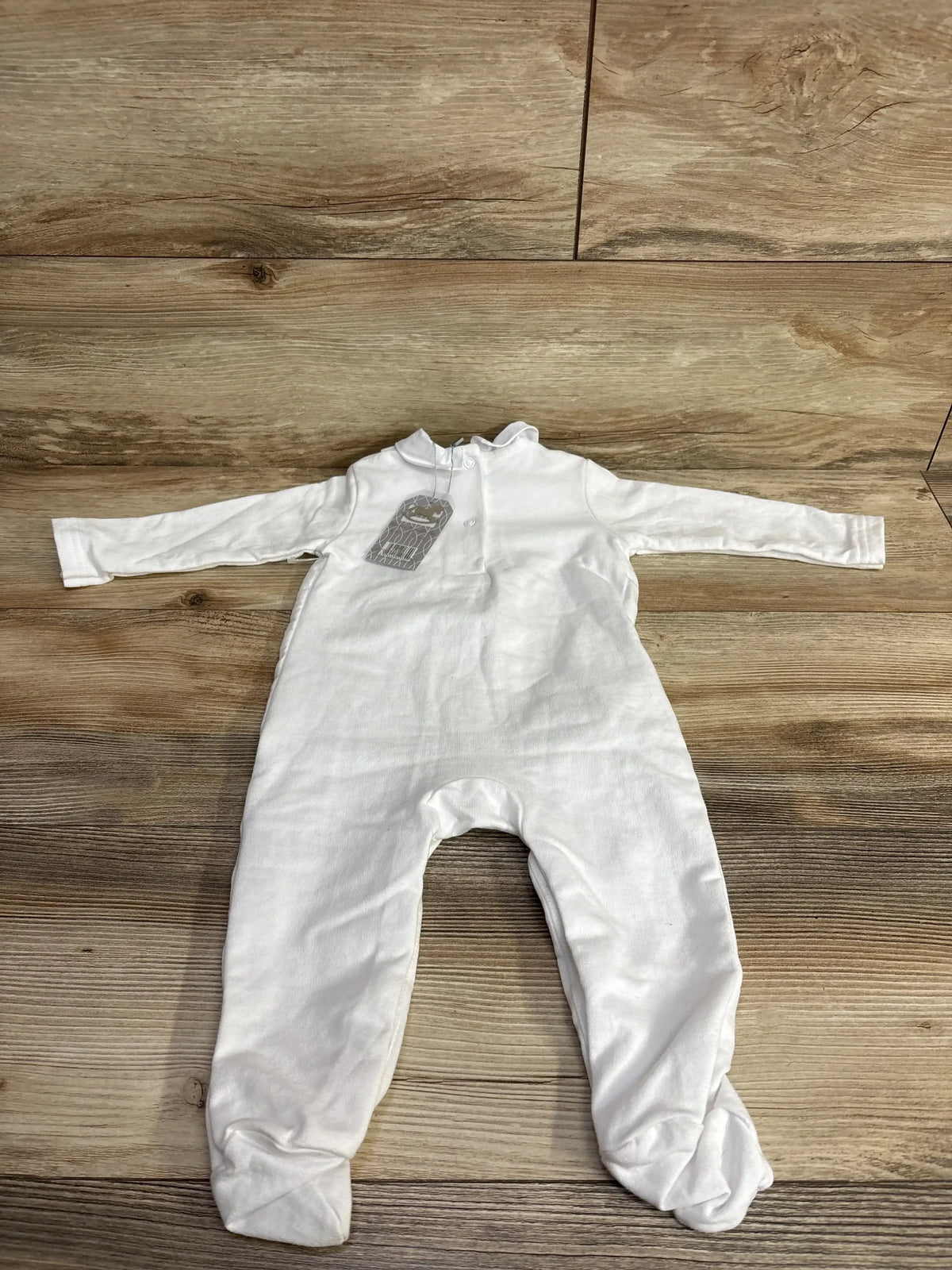 White long sleeve baby footed sleeper laid flat on wooden background