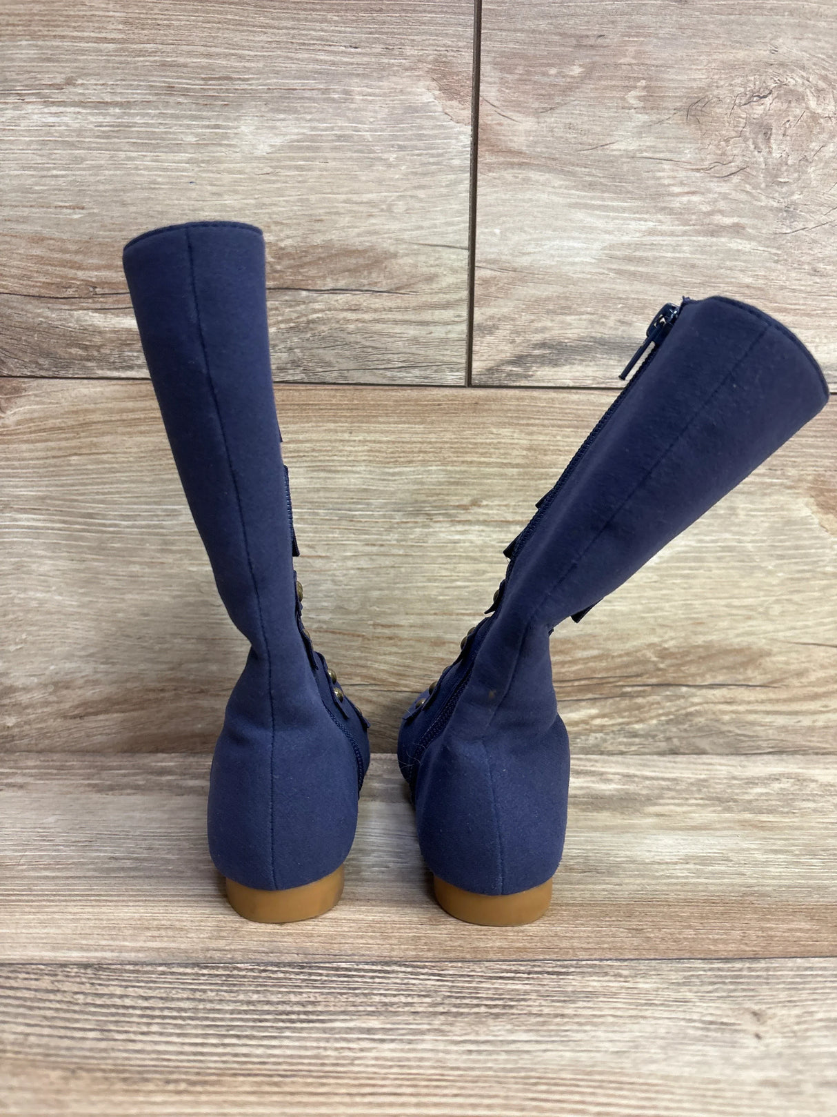 Rear view of Liv and Mia military style studded boots, navy size 8C, showing studs and side zipper on wooden floor