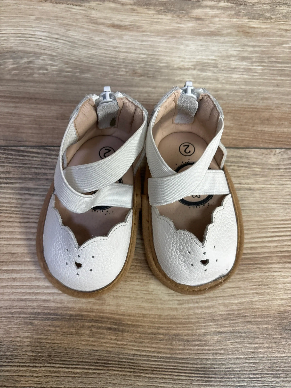 Top view of Little Love Bug The Sophia Mary Jane shoes in white with elastic strap and scalloped detail on wood plank floor